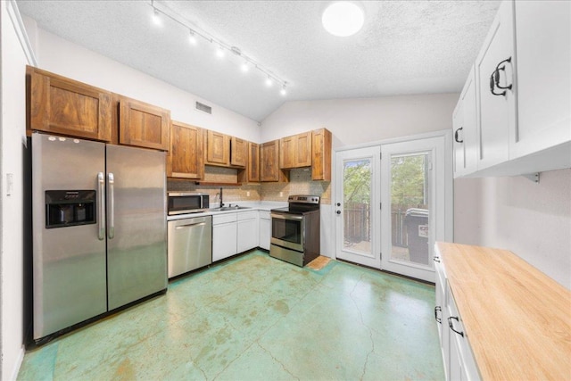 1015 E Yager Ln Unit 187, Austin, TX 78753 - kitchen featuring stainless steel appliances, a textured ceiling, a sink, tasteful backsplash, and lofted ceiling