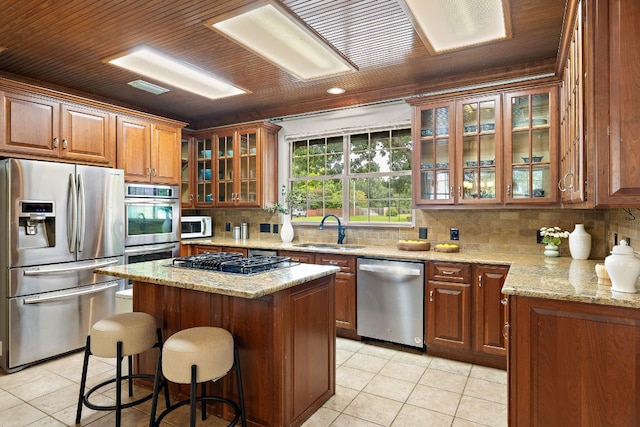 3 Hillview Dr, Round Rock, TX 78664 - kitchen with stainless steel appliances, a sink, light tile patterned floors, a kitchen island, and backsplash