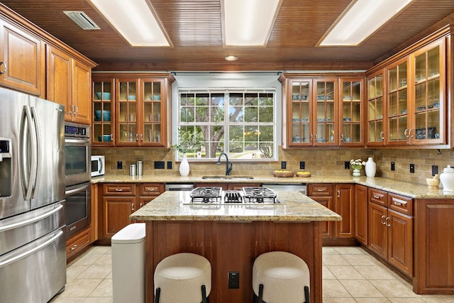 3 Hillview Dr, Round Rock, TX 78664 - kitchen featuring stainless steel appliances, a sink, brown cabinetry, light tile patterned flooring, and wooden ceiling