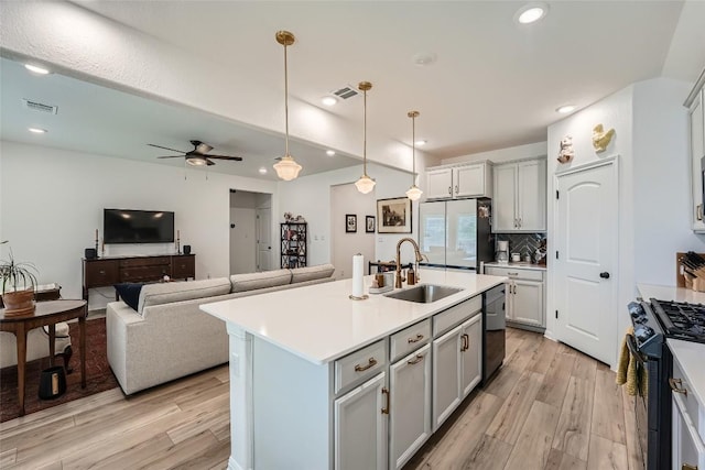 12904 Cerro Castellan Trce, Manor, TX 78653 - kitchen with black appliances, a sink, light wood finished floors, gray cabinets, and recessed lighting