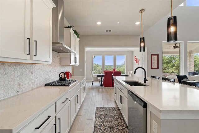 17804 Hattie Trce, Austin, TX 78738 - kitchen with appliances with stainless steel finishes, wall chimney exhaust hood, a sink, light wood-style flooring, and an island with sink