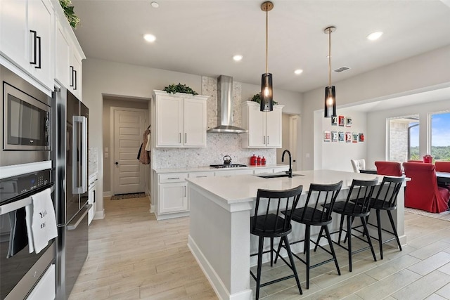 17804 Hattie Trce, Austin, TX 78738 - kitchen with wall chimney range hood, stainless steel appliances, light wood finished floors, light countertops, and recessed lighting
