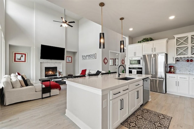 17804 Hattie Trce, Austin, TX 78738 - kitchen featuring appliances with stainless steel finishes, a sink, open floor plan, light wood finished floors, and white cabinetry