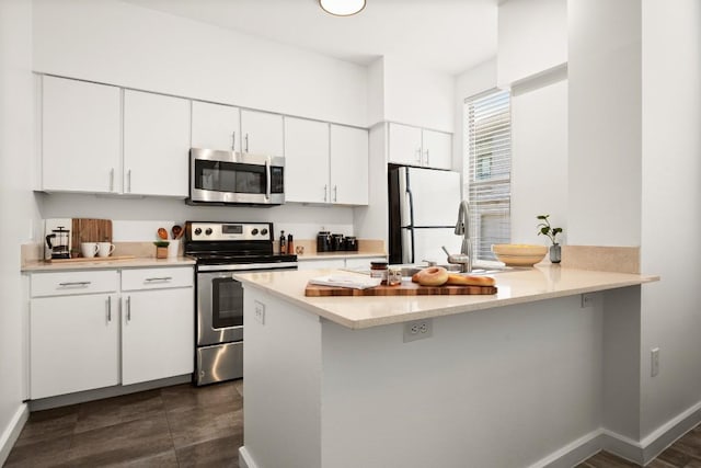 1201 Grove Blvd Unit 1103, Austin, TX 78741 - kitchen with stainless steel appliances, light countertops, white cabinetry, and a peninsula