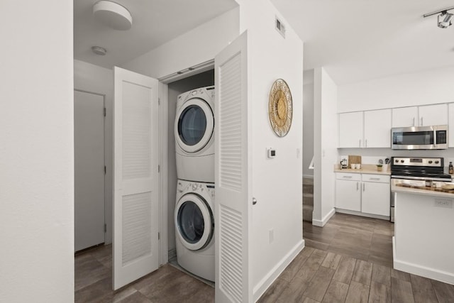 1201 Grove Blvd Unit 1103, Austin, TX 78741 - washroom featuring estacked washer and dryer, wood finished floors, and baseboards