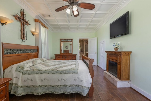 15055 Fm 32, Blanco, TX 78606 - bedroom featuring baseboards, dark wood-style floors, a fireplace with raised hearth, a ceiling fan, and an ornate ceiling