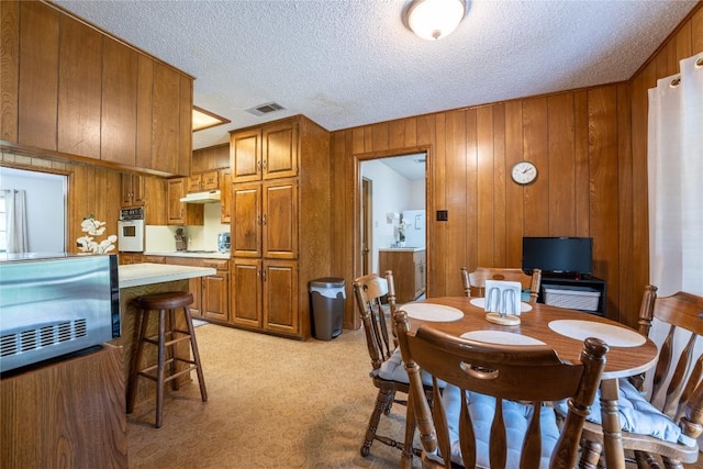 42 Laurel Hill St, Austin, TX 78737 - dining space with wood walls, a textured ceiling, and light colored carpet