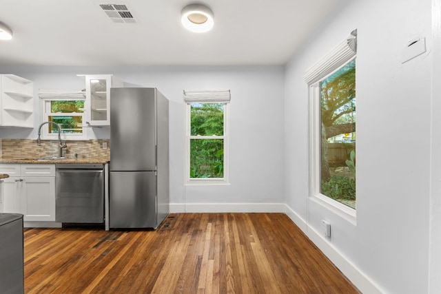 1904 S 6th St, Austin, TX 78704 - kitchen featuring appliances with stainless steel finishes, white cabinets, light stone counters, dark wood-style floors, and glass insert cabinets