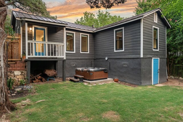 1904 S 6th St, Austin, TX 78704 - back of property at dusk featuring a hot tub, a metal roof, and a lawn