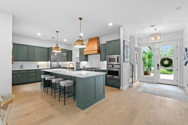 1708 Morrow St, Austin, TX 78757 - kitchen featuring green cabinetry, built in appliances, premium range hood, light countertops, and light wood-style flooring