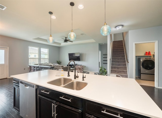 6900 Midlothian Dr, Austin, TX 78754 - kitchen with stainless steel dishwasher, washer / clothes dryer, a sink, dark cabinetry, and a tray ceiling