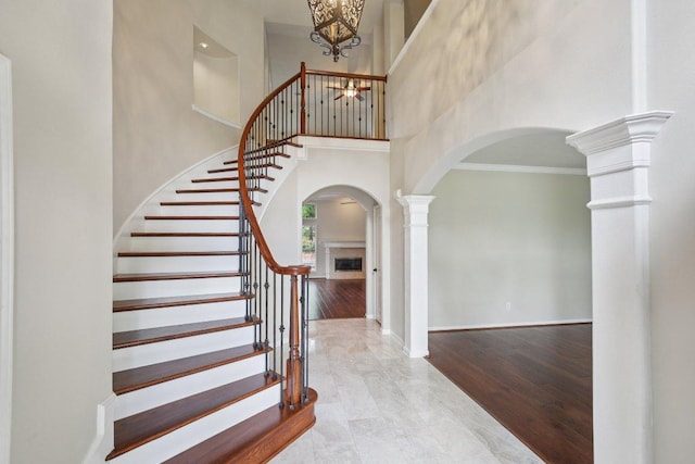 6611 Haughton Dr, Spring, TX 77389 - stairs featuring arched walkways, a towering ceiling, decorative columns, crown molding, and a chandelier