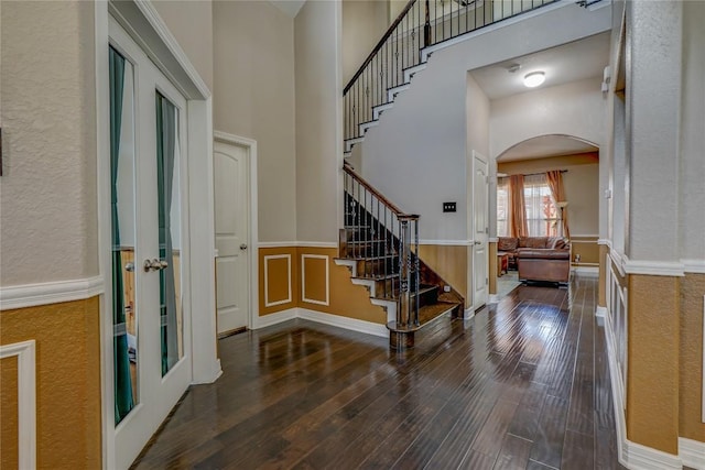 3107 Magnolia Mnr, New Braunfels, TX 78130 - entrance foyer featuring arched walkways, wood finished floors, a wainscoted wall, stairs, and a towering ceiling