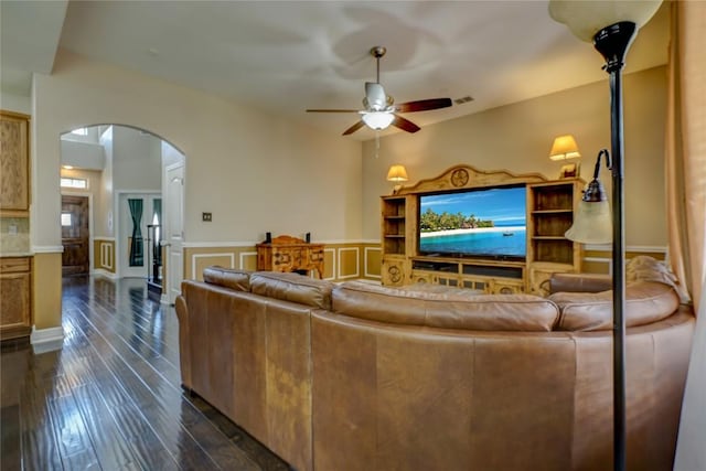 3107 Magnolia Mnr, New Braunfels, TX 78130 - living area with arched walkways, a ceiling fan, wainscoting, dark wood-style flooring, and a decorative wall