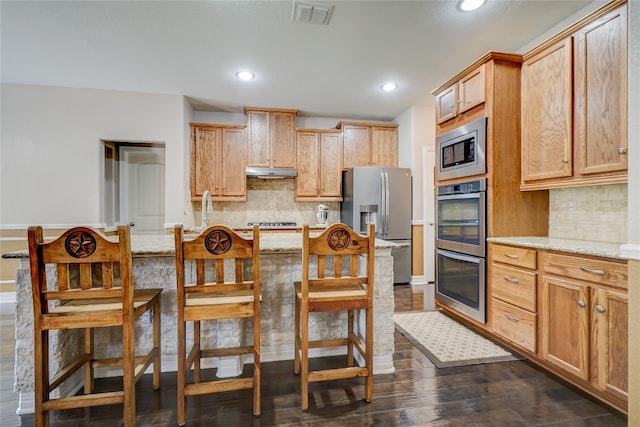 3107 Magnolia Mnr, New Braunfels, TX 78130 - kitchen with stainless steel appliances, under cabinet range hood, backsplash, recessed lighting, and dark wood-type flooring