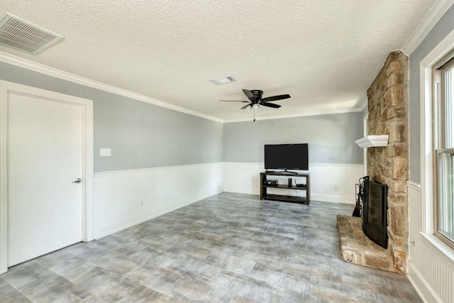 1506 Spiderlily Vw, Cedar Park, TX 78613 - unfurnished living room featuring wainscoting, a textured ceiling, wood finished floors, a ceiling fan, and a stone fireplace