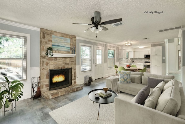 1506 Spiderlily Vw, Cedar Park, TX 78613 - living area featuring crown molding, plenty of natural light, a textured ceiling, a ceiling fan, and a fireplace