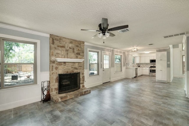 1506 Spiderlily Vw, Cedar Park, TX 78613 - unfurnished living room with ornamental molding, a textured ceiling, a ceiling fan, a stone fireplace, and wood finished floors