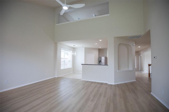 2308 Lou John St, Austin, TX 78727 - unfurnished living room featuring a high ceiling, light wood-style floors, a ceiling fan, baseboards, and arched walkways