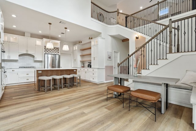 800 Newcastle Dr, Austin, TX 78745 - kitchen with appliances with stainless steel finishes, light wood-style flooring, open shelves, a kitchen island, and white cabinetry