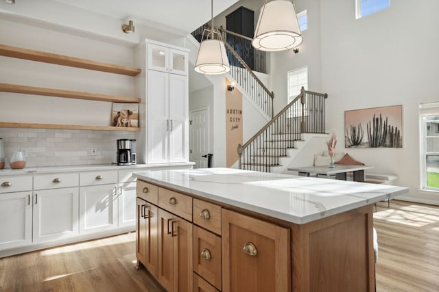 800 Newcastle Dr, Austin, TX 78745 - kitchen featuring open shelves, light wood finished floors, a towering ceiling, tasteful backsplash, and white cabinetry