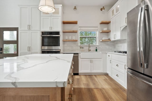 800 Newcastle Dr, Austin, TX 78745 - kitchen with stainless steel appliances, open shelves, light wood-style floors, and white cabinets