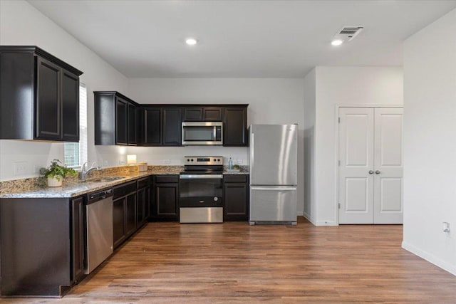 336 Wonderful Life Way, Jarrell, TX 76537 - kitchen with appliances with stainless steel finishes, a sink, wood finished floors, light stone countertops, and baseboards