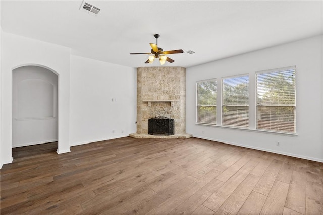 250 Maeves Way, Austin, TX 78737 - unfurnished living room with ceiling fan, wood finished floors, a fireplace, arched walkways, and baseboards