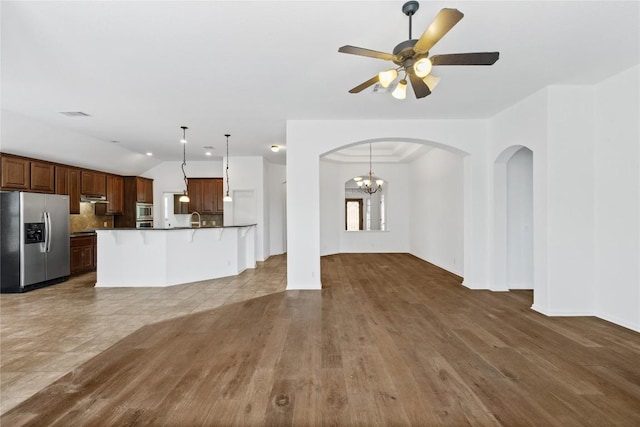 250 Maeves Way, Austin, TX 78737 - unfurnished living room featuring vaulted ceiling, arched walkways, ceiling fan, a sink, and wood finished floors
