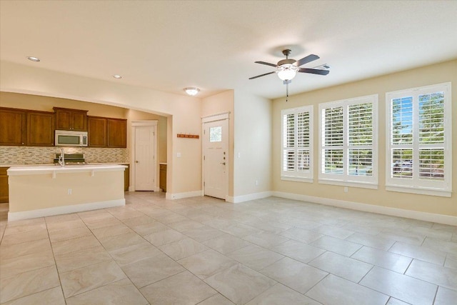 10908 Railway Ln Unit 76, Austin, TX 78717 - kitchen with white microwave, light countertops, decorative backsplash, a ceiling fan, and brown cabinets