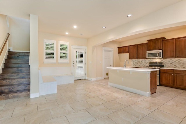 10908 Railway Ln Unit 76, Austin, TX 78717 - kitchen featuring stainless steel appliances, decorative backsplash, light countertops, a center island with sink, and brown cabinetry