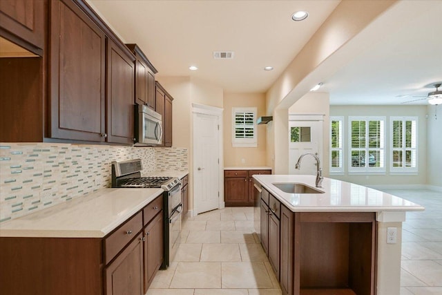 10908 Railway Ln Unit 76, Austin, TX 78717 - kitchen featuring appliances with stainless steel finishes, a sink, backsplash, a kitchen island with sink, and light countertops
