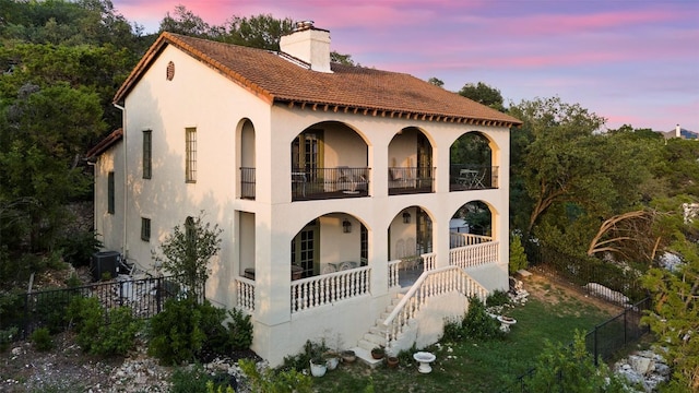 6203 Ledge Mountain Dr, Austin, TX 78731 - mediterranean / spanish home featuring a balcony, a chimney, stucco siding, a porch, and central AC unit