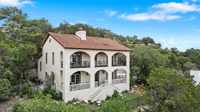 6203 Ledge Mountain Dr, Austin, TX 78731 - view of front of home with a balcony, a chimney, a porch, stucco siding, and stairway