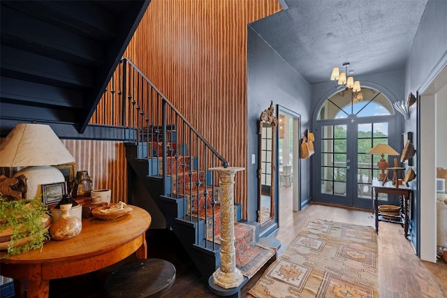 6203 Ledge Mountain Dr, Austin, TX 78731 - staircase featuring wood finished floors, a chandelier, a textured ceiling, and french doors