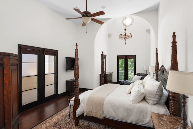 4256 Fischer Store Rd, Wimberley, TX 78676 - bedroom featuring arched walkways, french doors, dark wood-style flooring, a chandelier, and a high ceiling