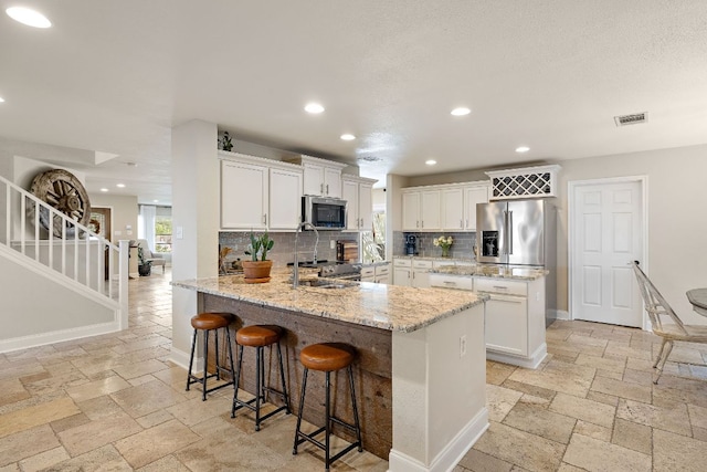 1705 Chinati Ct, Cedar Park, TX 78613 - kitchen with stainless steel appliances, a peninsula, stone tile flooring, tasteful backsplash, and white cabinetry