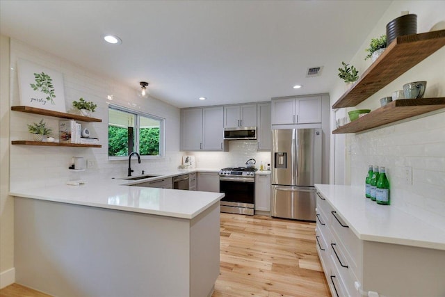 12801 Oak Bend Cv, Austin, TX 78727 - kitchen featuring stainless steel appliances, open shelves, a peninsula, backsplash, and recessed lighting