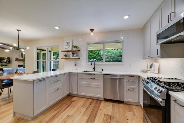 12801 Oak Bend Cv, Austin, TX 78727 - kitchen featuring stainless steel appliances, a sink, a peninsula, decorative backsplash, and plenty of natural light