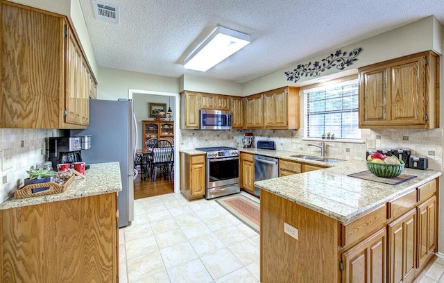 14309 Richard Walker Blvd, Austin, TX 78728 - kitchen featuring stainless steel appliances, a sink, a peninsula, backsplash, and a textured ceiling