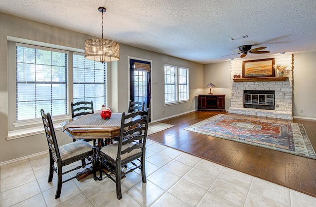 14309 Richard Walker Blvd, Austin, TX 78728 - dining room featuring a ceiling fan, baseboards, a textured ceiling, tile patterned flooring, and a fireplace
