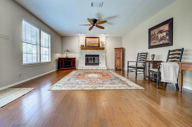 14309 Richard Walker Blvd, Austin, TX 78728 - living room with healthy amount of natural light, a ceiling fan, wood-type flooring, a textured ceiling, and a fireplace