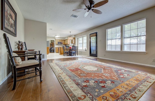 14309 Richard Walker Blvd, Austin, TX 78728 - living area with dark wood-style floors, ceiling fan, a textured ceiling, a chandelier, and baseboards