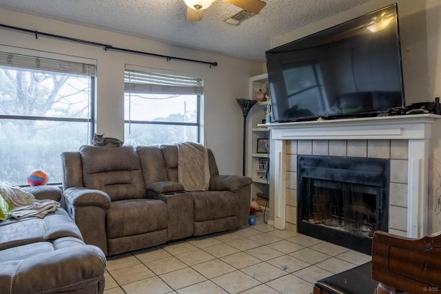 2903 W Slaughter Ln, Austin, TX 78748 - living area with a textured ceiling, light tile patterned flooring, a ceiling fan, and a tiled fireplace