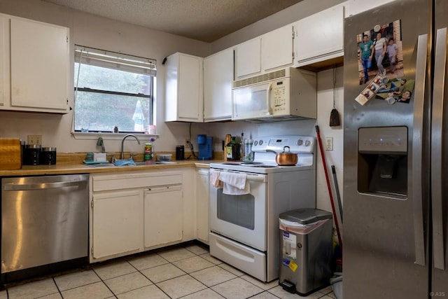 2903 W Slaughter Ln, Austin, TX 78748 - kitchen with stainless steel appliances, a sink, light countertops, a textured ceiling, and white cabinets