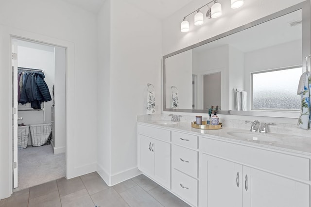 104 Meadow Wood Cv, Georgetown, TX 78626 - bathroom with double vanity, a walk in closet, tile patterned flooring, and baseboards
