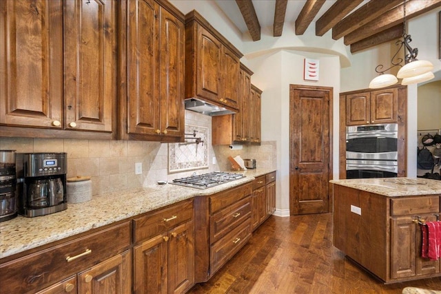 102 Standing Oak Dr, Georgetown, TX 78633 - kitchen with stainless steel appliances, backsplash, light stone countertops, under cabinet range hood, and beam ceiling