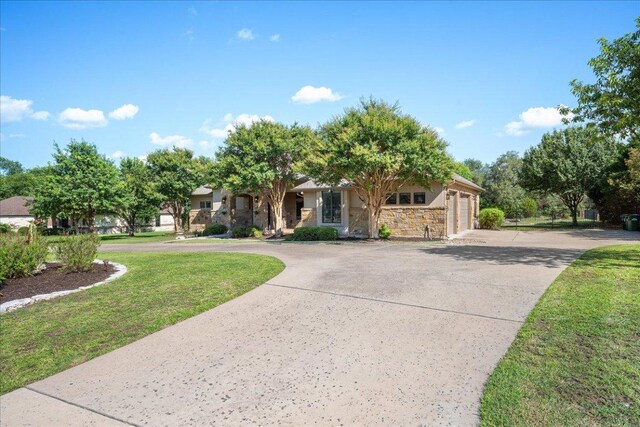 102 Standing Oak Dr, Georgetown, TX 78633 - view of property hidden behind natural elements featuring curved driveway, an attached garage, stone siding, and a front yard