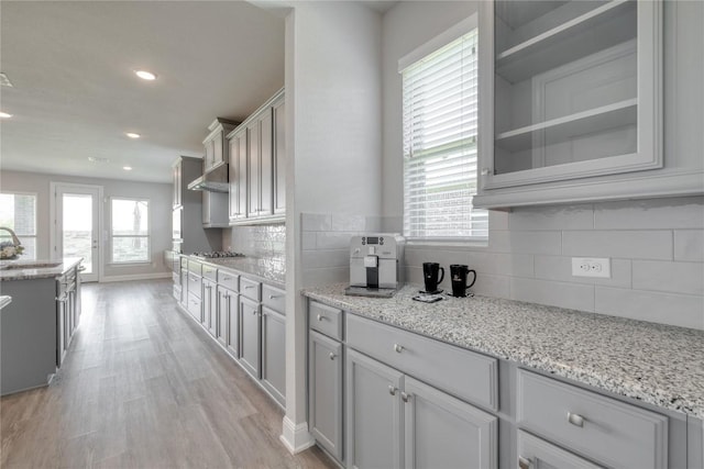 3241 Aurelia Ln, Round Rock, TX 78665 - kitchen with light wood finished floors, decorative backsplash, light stone countertops, glass insert cabinets, and recessed lighting
