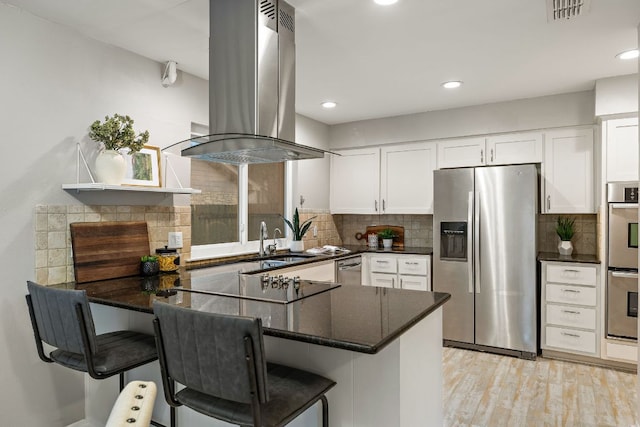 13007 Stillforest St, Austin, TX 78729 - kitchen with appliances with stainless steel finishes, island range hood, a peninsula, white cabinetry, and backsplash